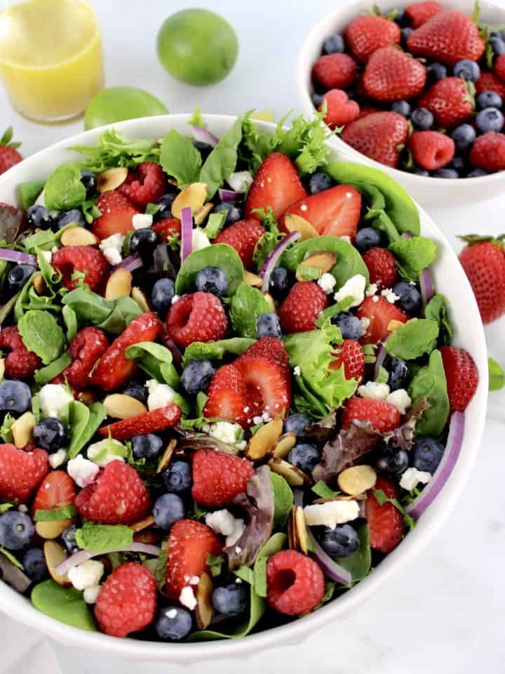 Triple Berry Salad in white bowl with berries and dressing in back