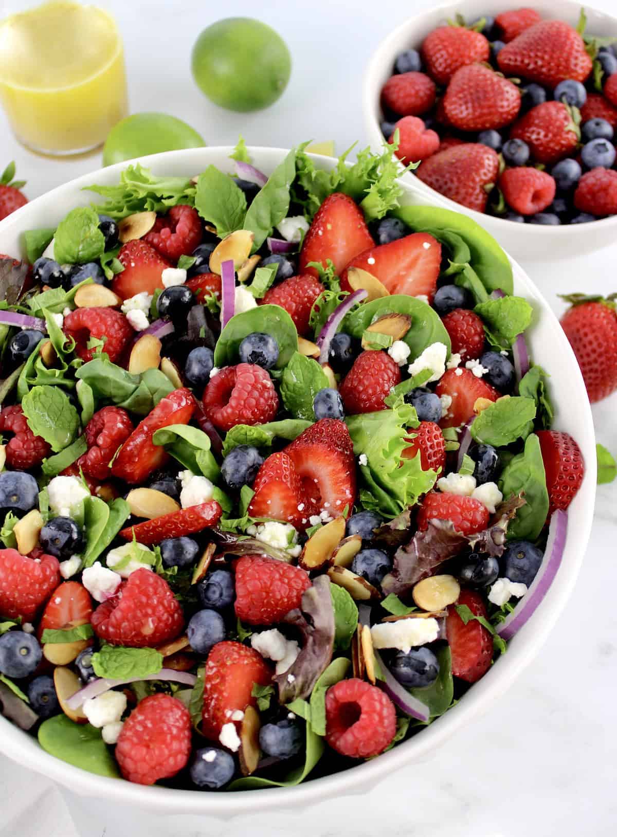 Triple Berry Salad in white bowl with berries and dressing in back