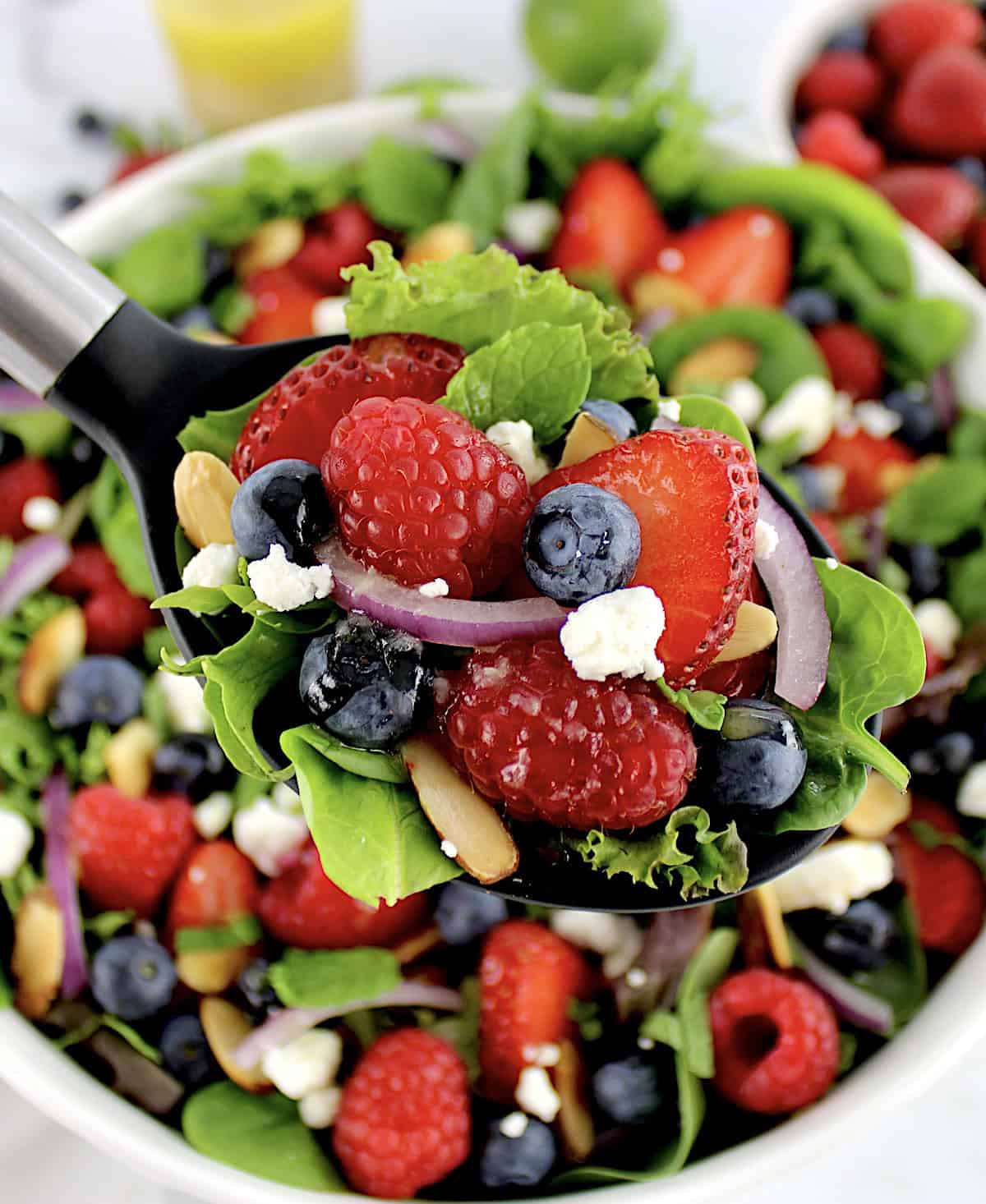 Triple Berry Salad with serving spoon holding up some