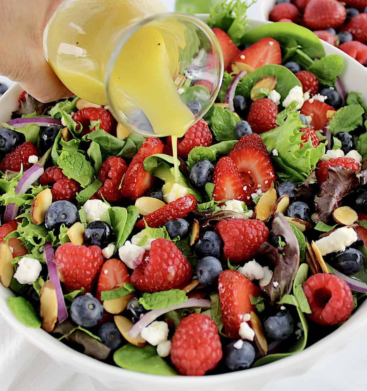 Triple Berry Salad with dressing being poured over the top