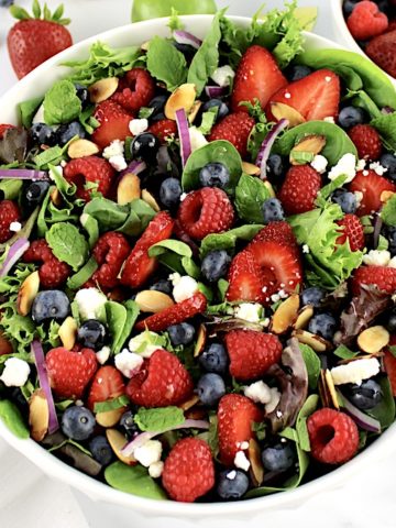 overhead view of Triple Berry Salad in white bowl with berries in back