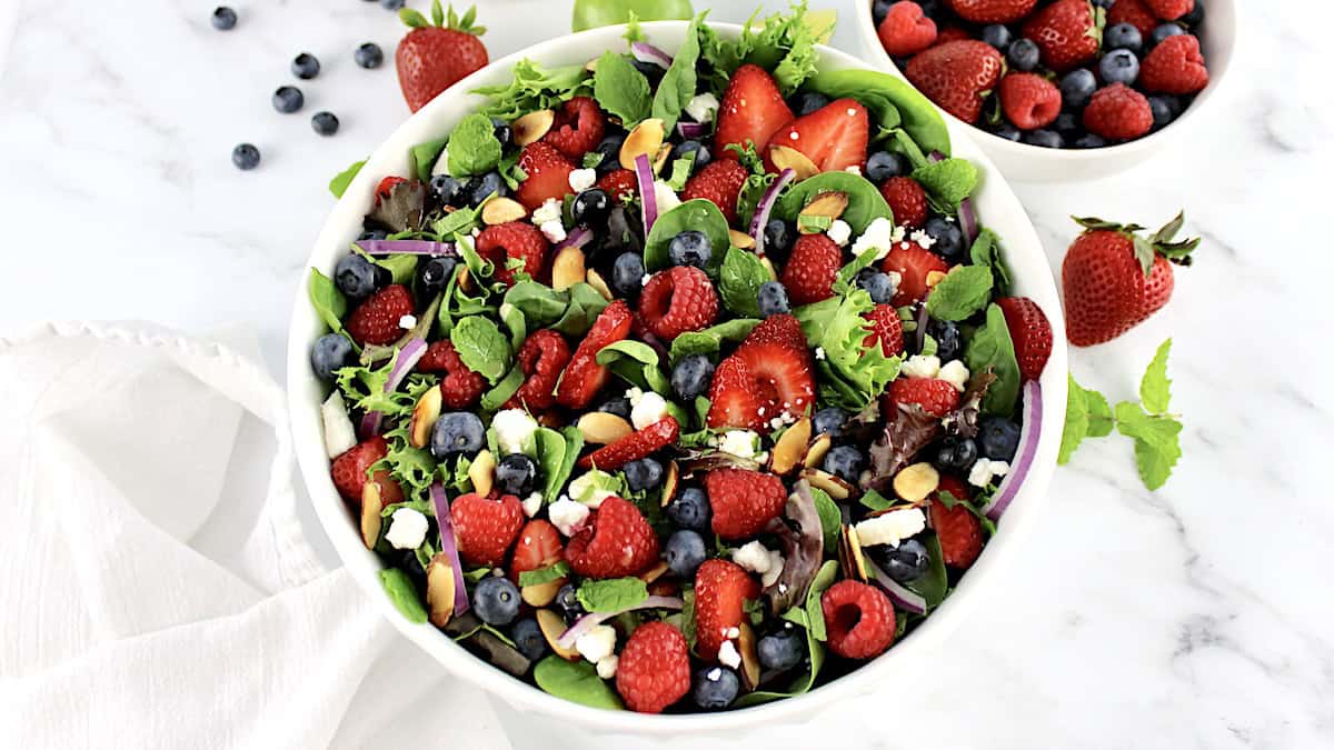 overhead view of Triple Berry Salad in white bowl with berries in back