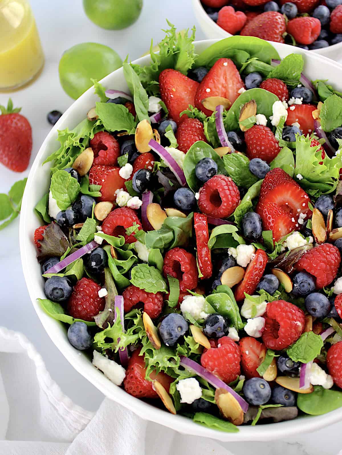 Triple Berry Salad in white bowl with berries and dressing in back