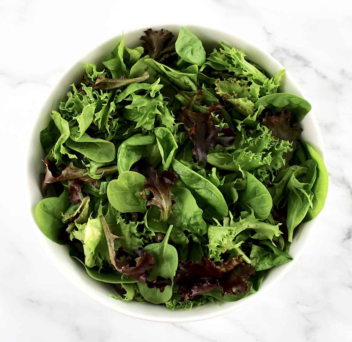 overhead view of mixed greens in white bowl