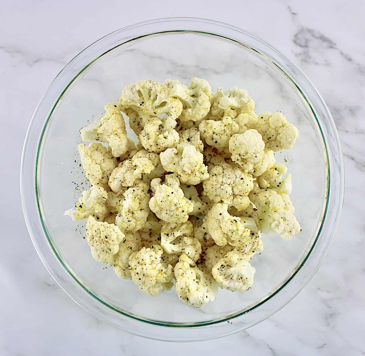 cauliflower florets, olive oil, garlic salt and pepper in glass bowl