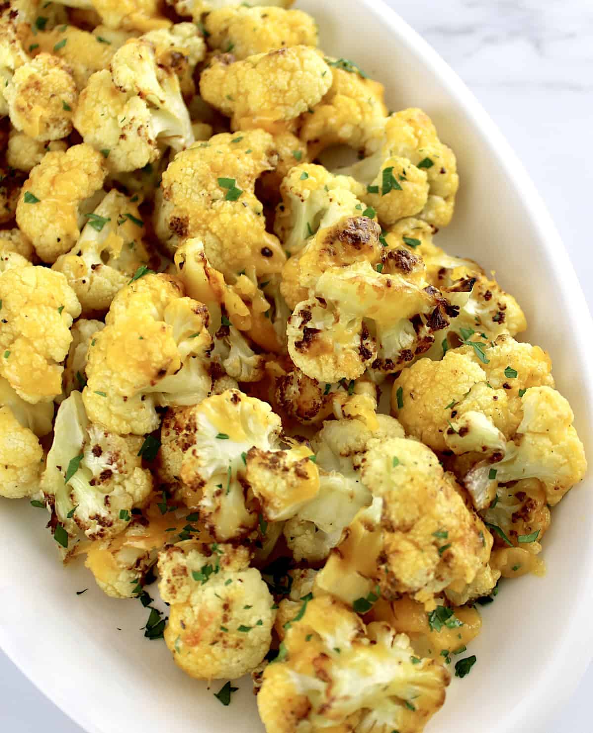 Air Fryer Cheesy Cauliflower in white oval platter with chopped parsley on top