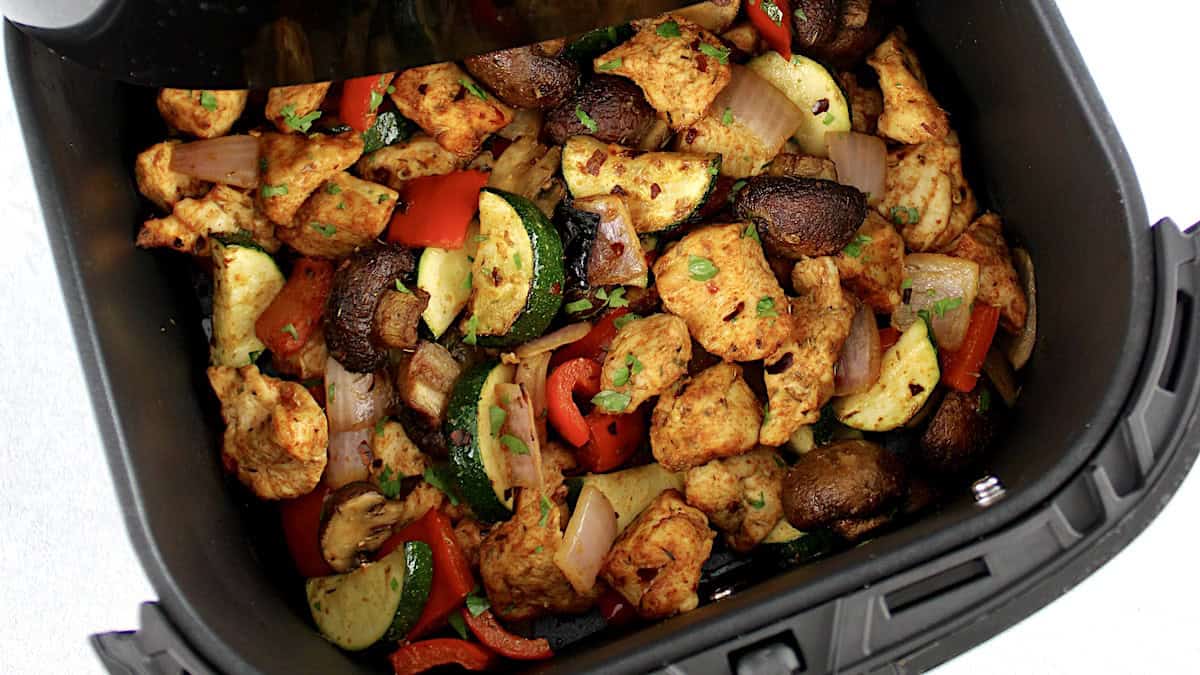 Air Fryer Chicken Bites and Veggies in air fryer basket with chopped parsley