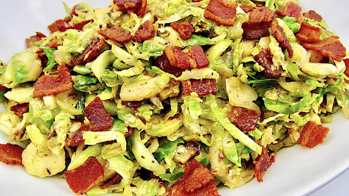 closeup of Brussels Sprouts with Hot Bacon Dressing in white bowl with bacon on top