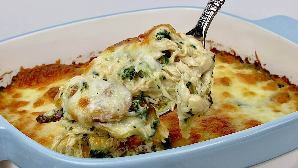 Chicken Alfredo Casserole being scooped out of blue casserole dish