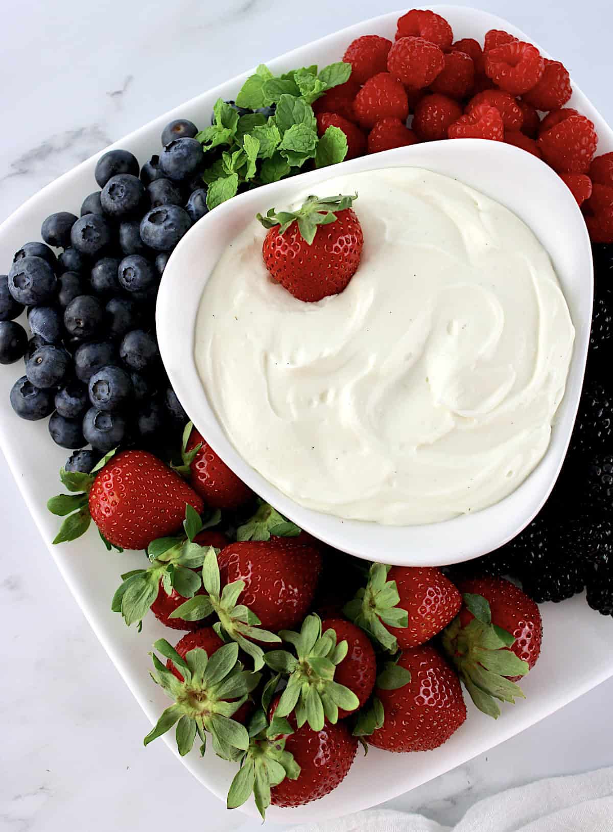 Easy Fruit Dip in white bowl with fresh berries all around