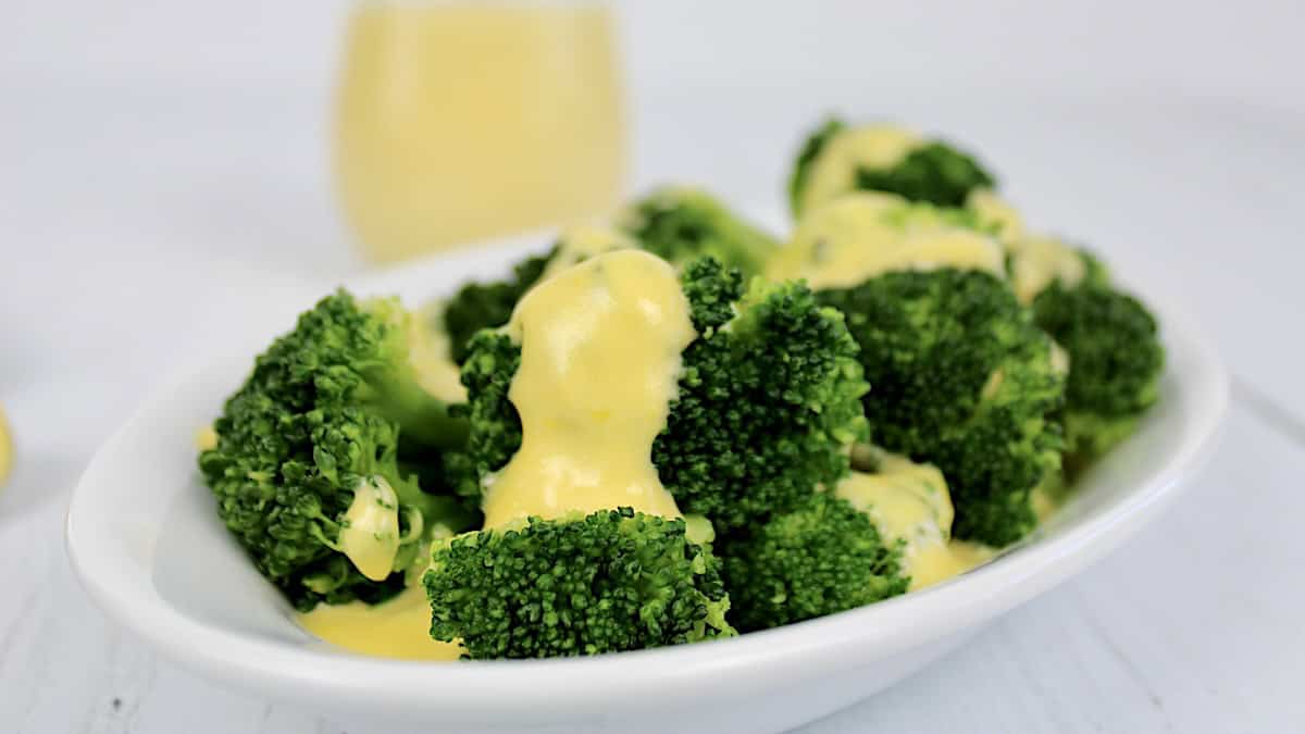 cheese sauce over broccoli on white plate