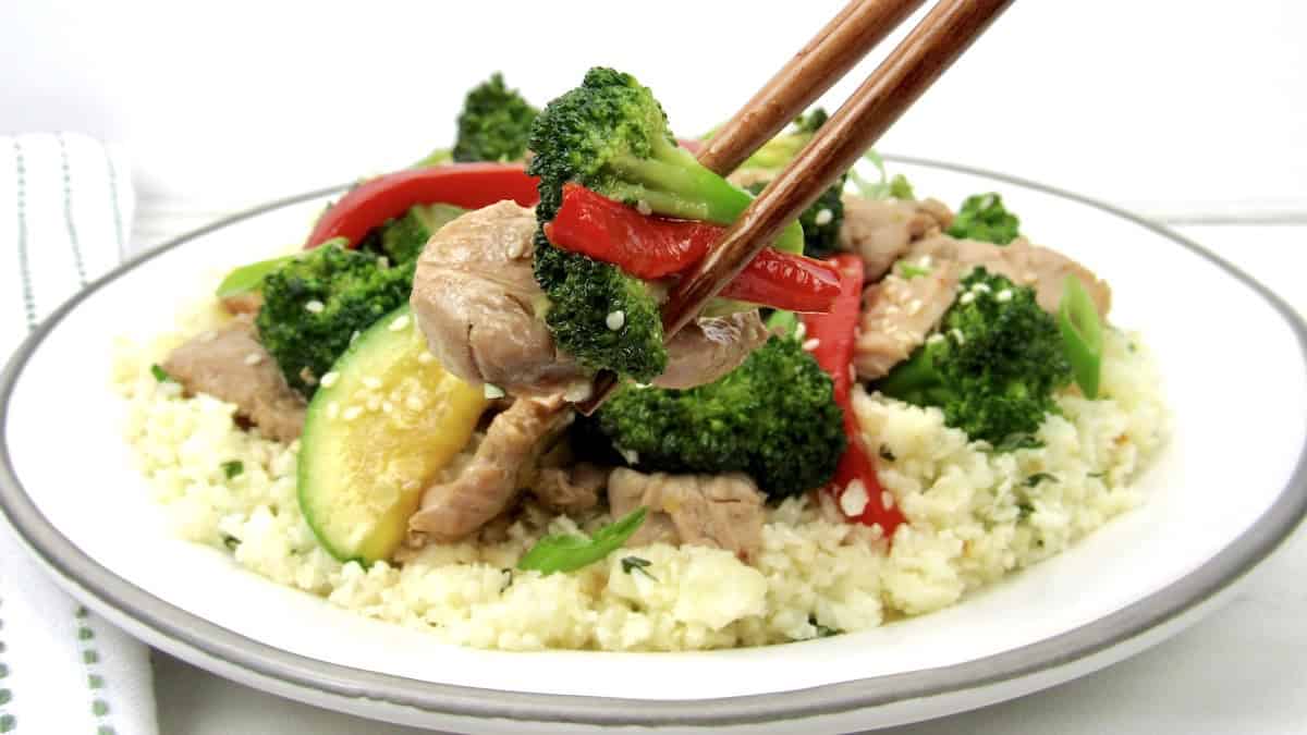 Easy Stir Fry Pork over plate of cauliflower rice with chopsticks