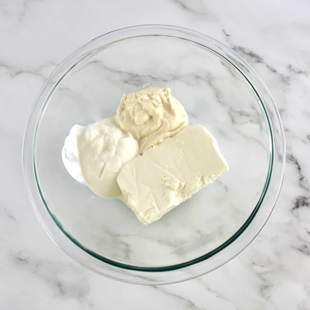 cream cheese, mayonnaise and sour cream in glass bowl unmixed