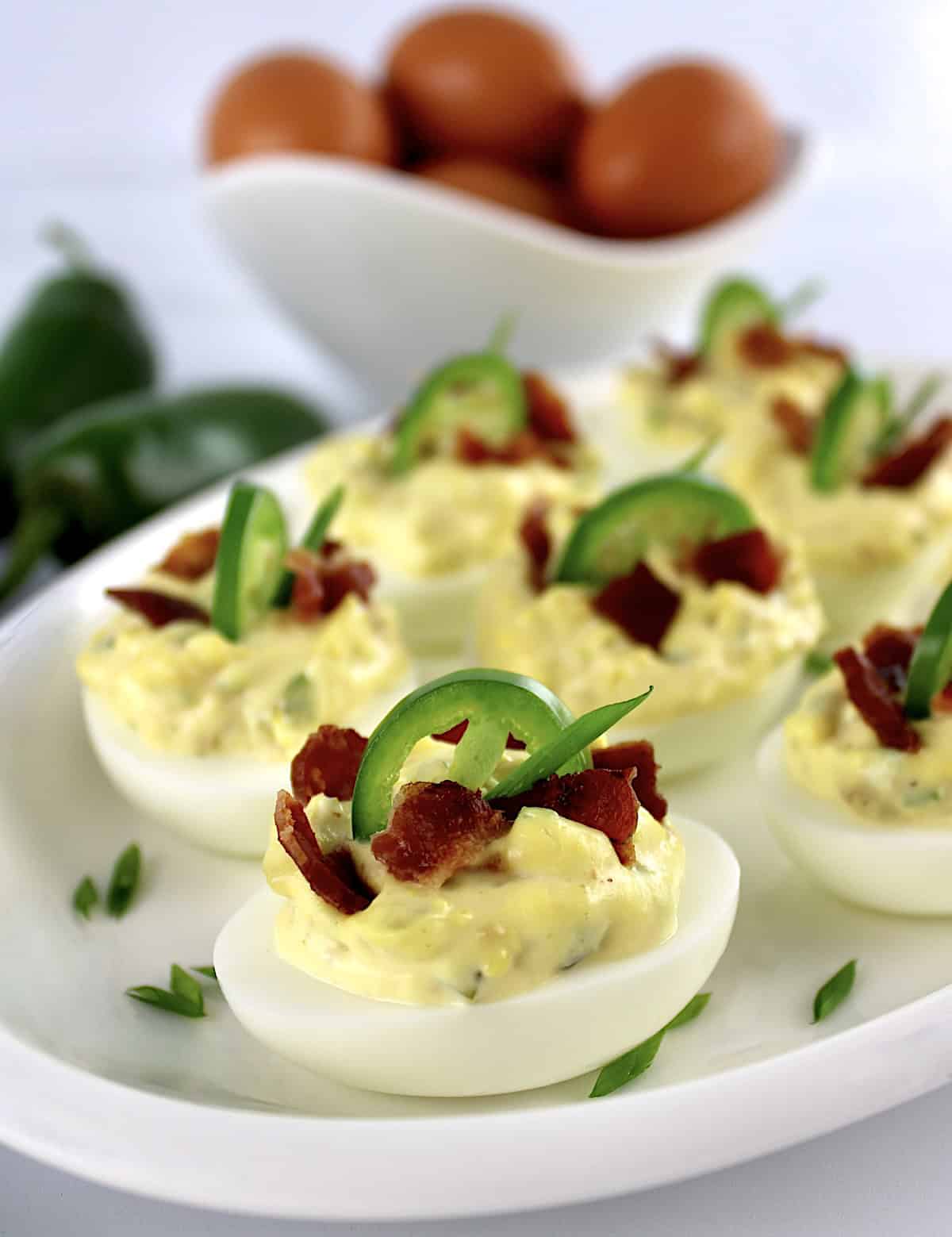 Jalapeño Popper Deviled Eggs on white platter with eggs in back