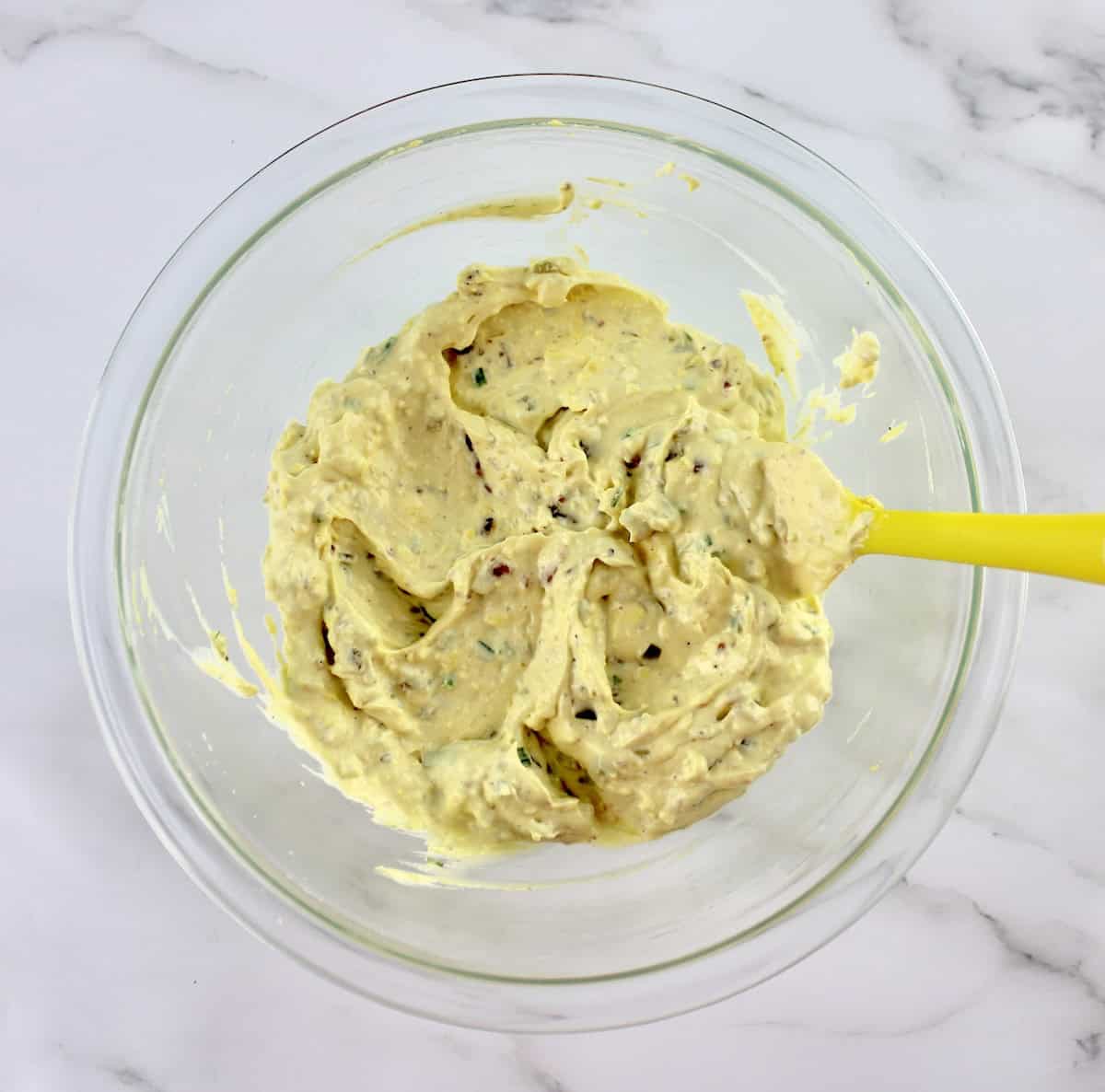 Jalapeño Popper Deviled Eggs stuffing in glass bowl with yellow spoon