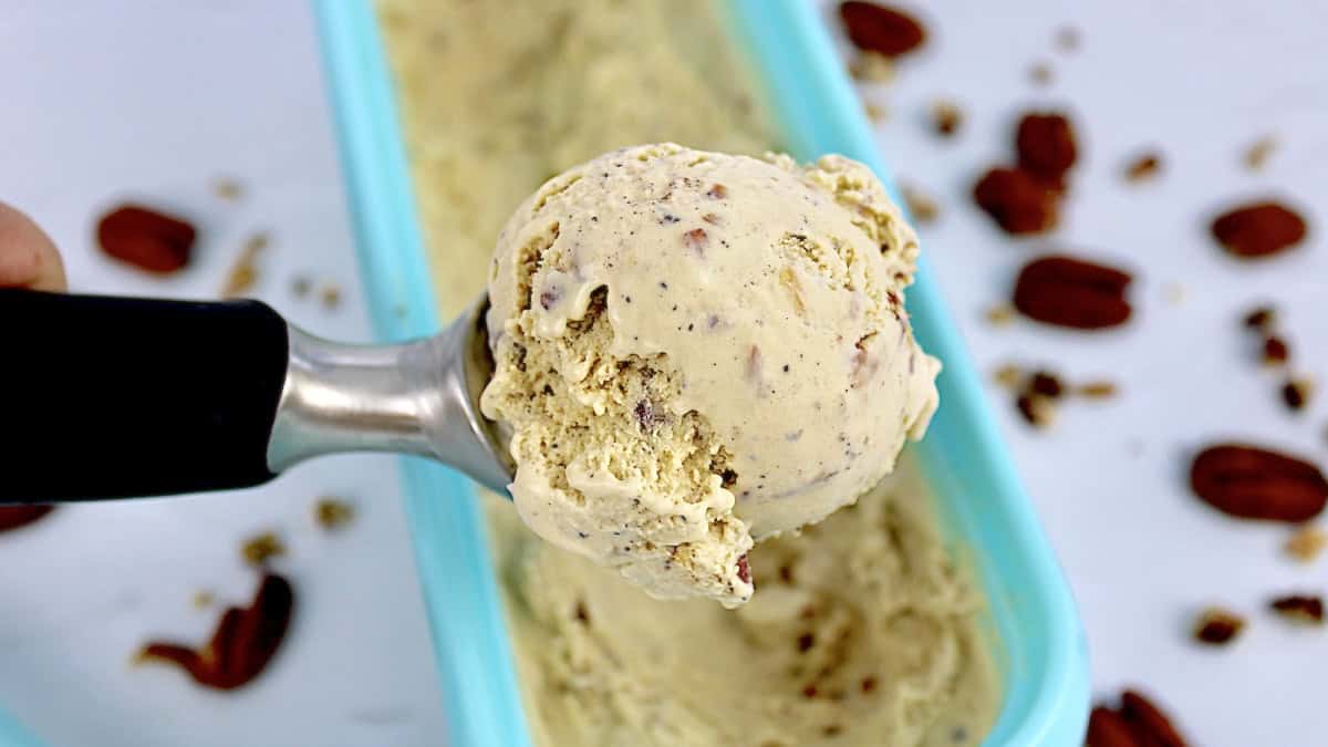 Keto Butter Pecan Ice Cream in scoop held up over blue ice cream container