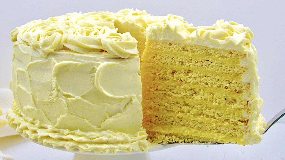 Keto Lemon Curd Layer Cake on cake stand with slice being removed