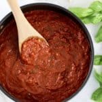 Keto Marinara Sauce in saucepan with wooden spoon and basil on side