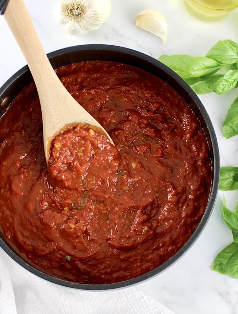 Keto Marinara Sauce in saucepan with wooden spoon and basil on side