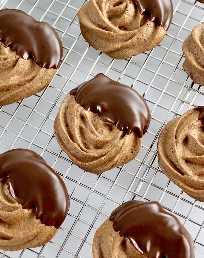 Mocha Meringue Cookies half dipped in chocolate on cooking rack