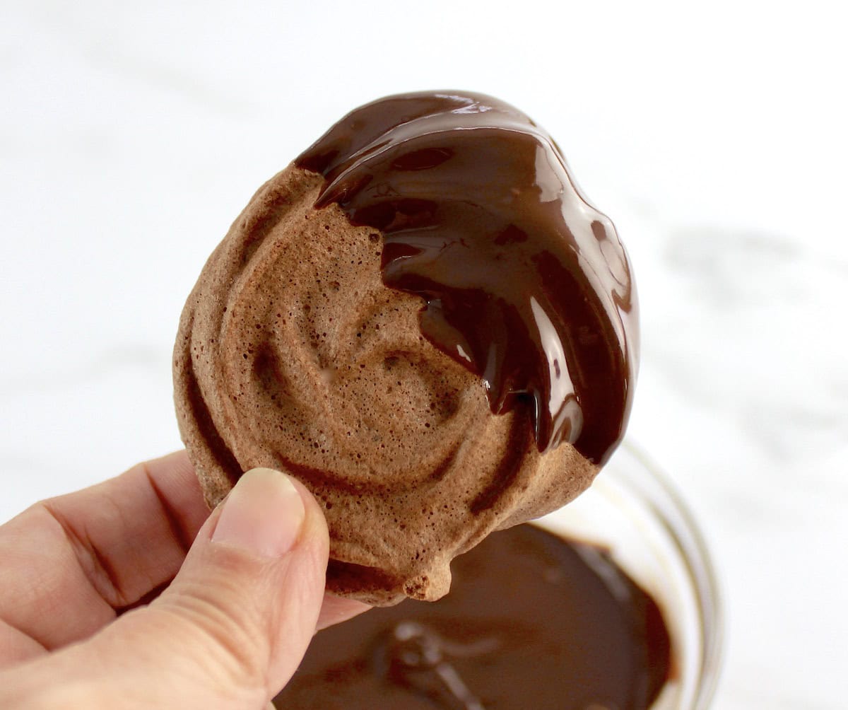 chocolate dipped Mocha Meringue Cookie being held up