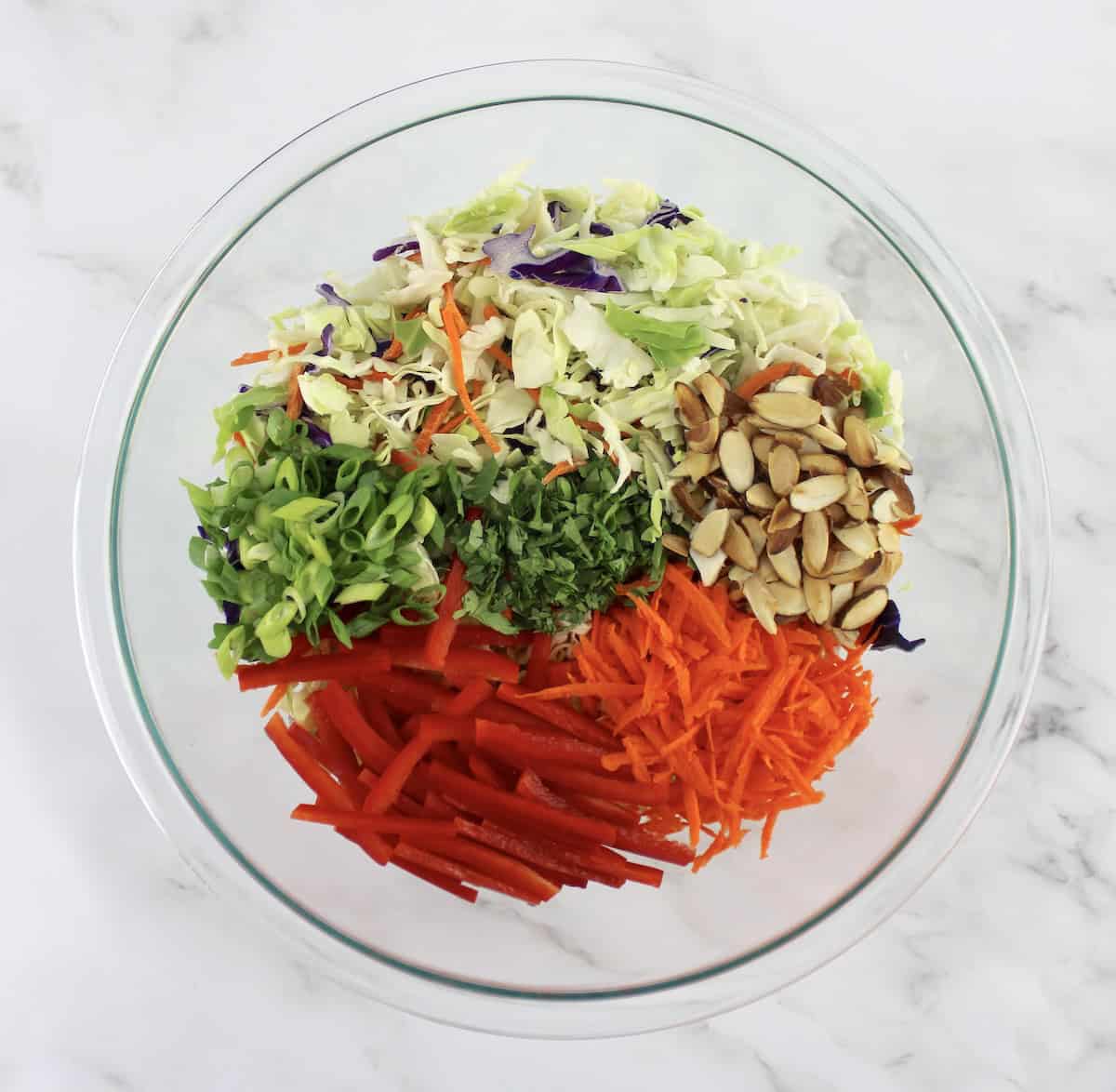 Peanut Ginger Slaw ingredients in groups in glass bowl umixed