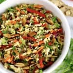 Peanut Ginger Slaw in white bowl with scallions carrots and ginger in background