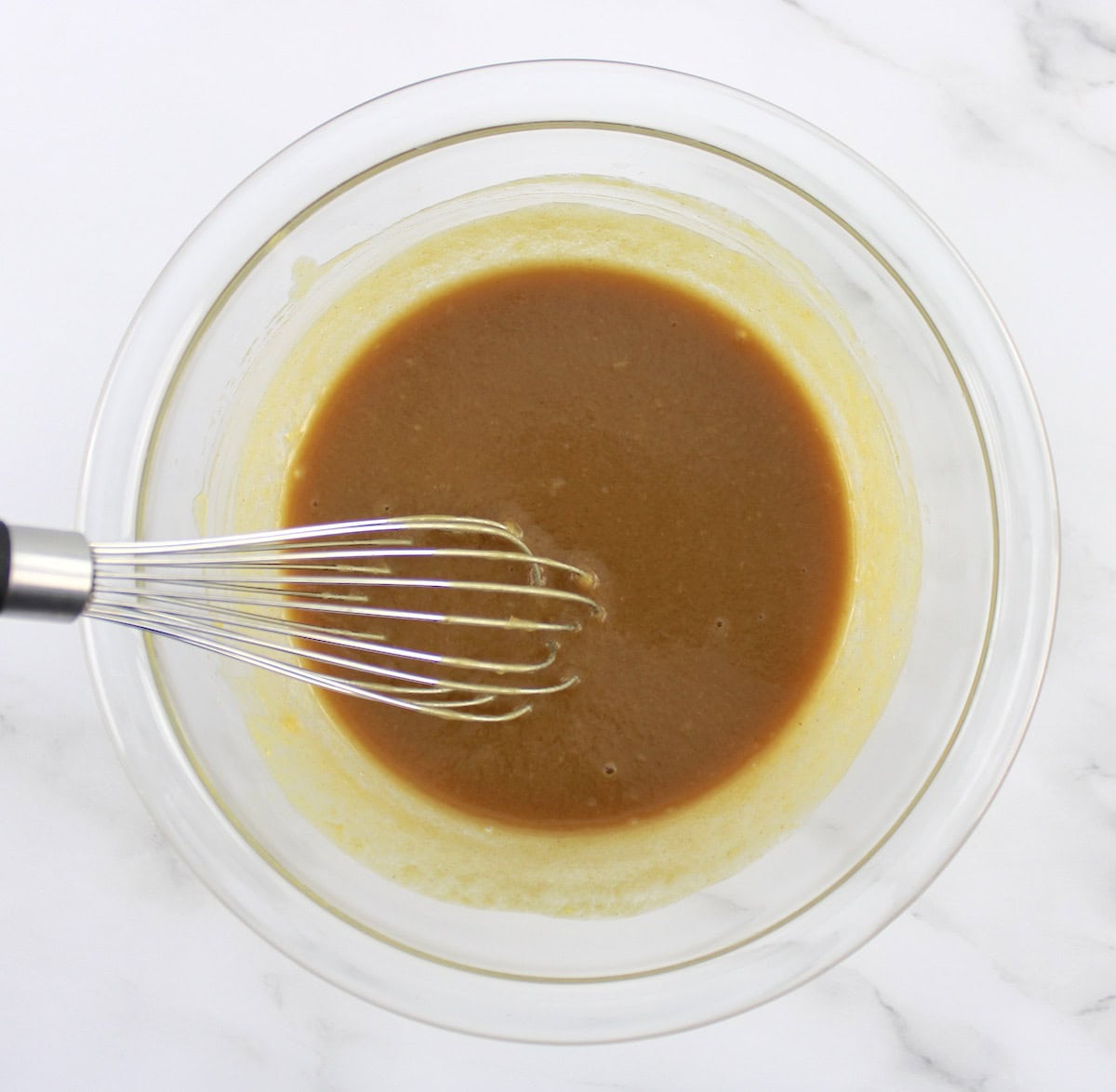 Peanut Ginger Slaw dressing in glass bowl with whisk