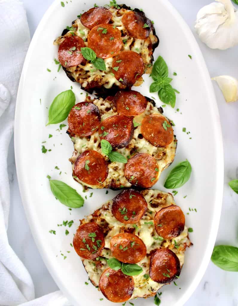 3 Portobello Mushroom Mini Pizzas on white platter with fresh basil leaves