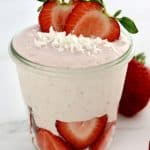 Strawberry Coconut Cream Mousse in glass jar with sliced strawberries on bottom and top with shredded coconut