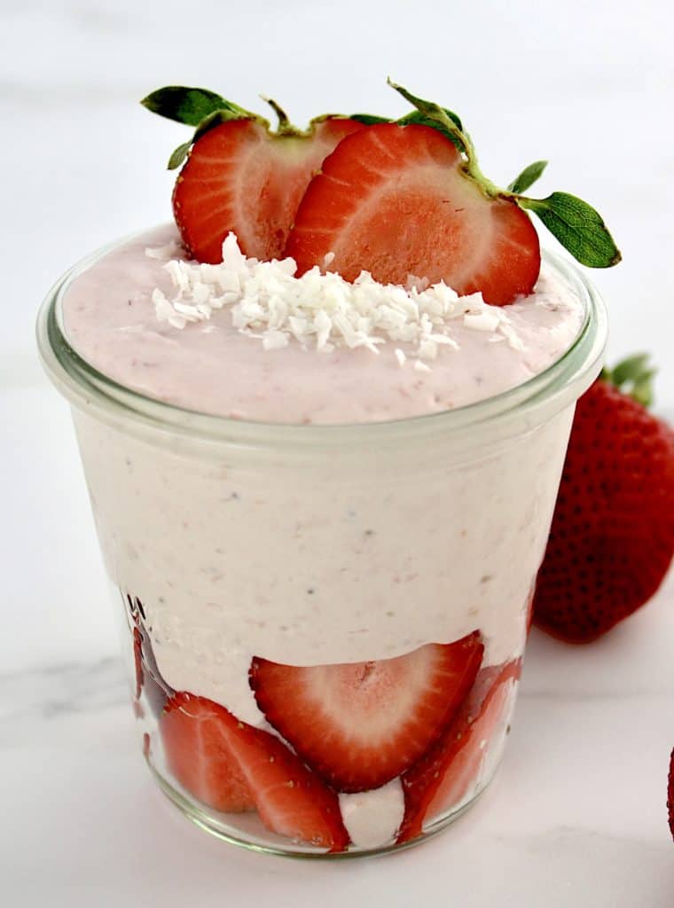 Strawberry Coconut Cream Mousse in glass jar with sliced strawberries on bottom and top with shredded coconut