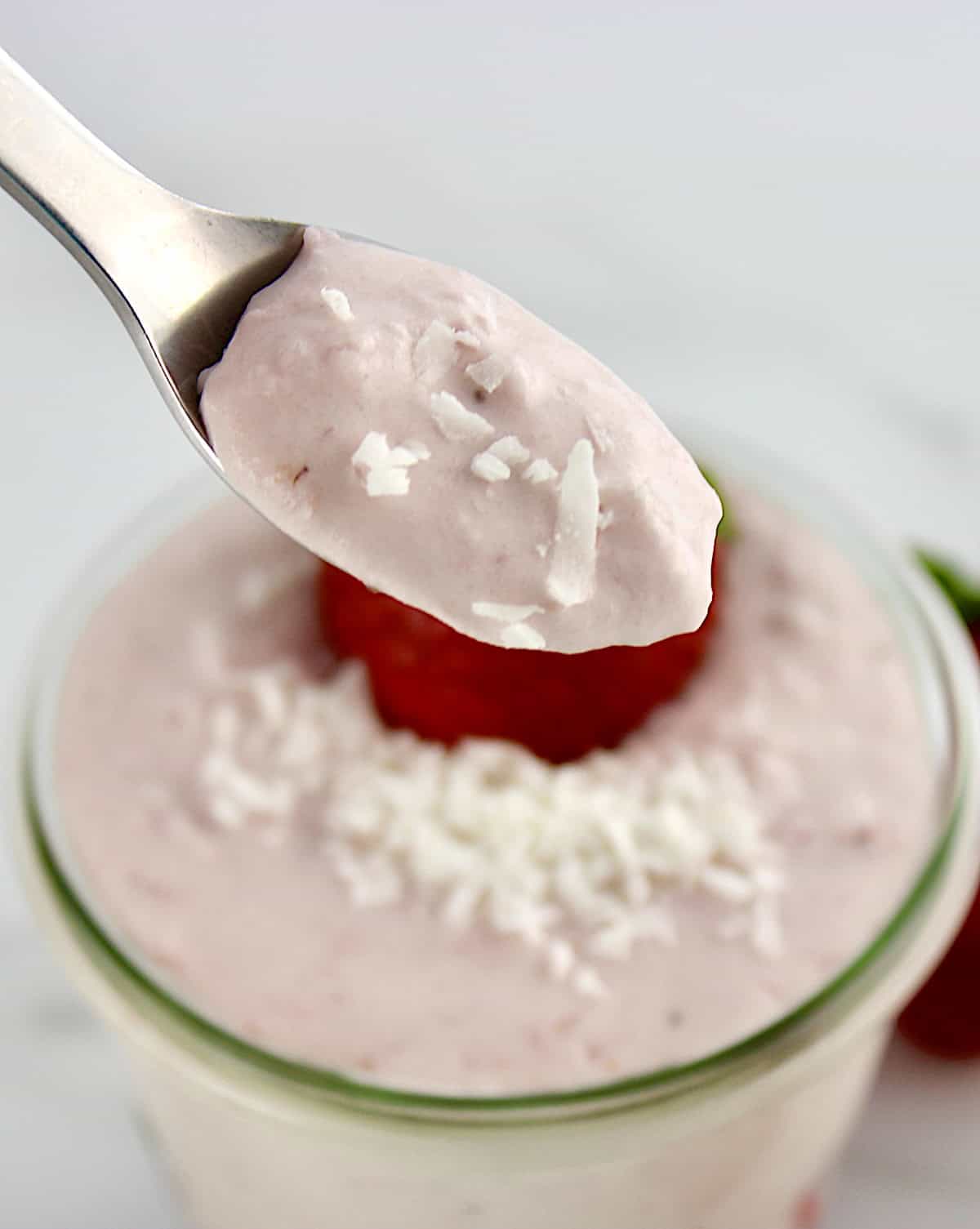 Strawberry Coconut Cream Mousse in spoon held up over glass jar