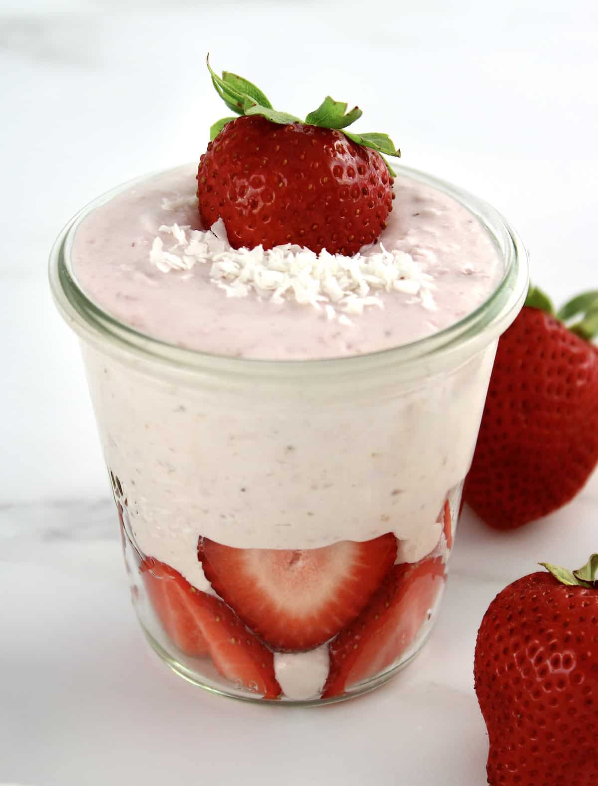 Strawberry Coconut Cream Mousse in glass jar with sliced strawberries on bottom and top with shredded coconut