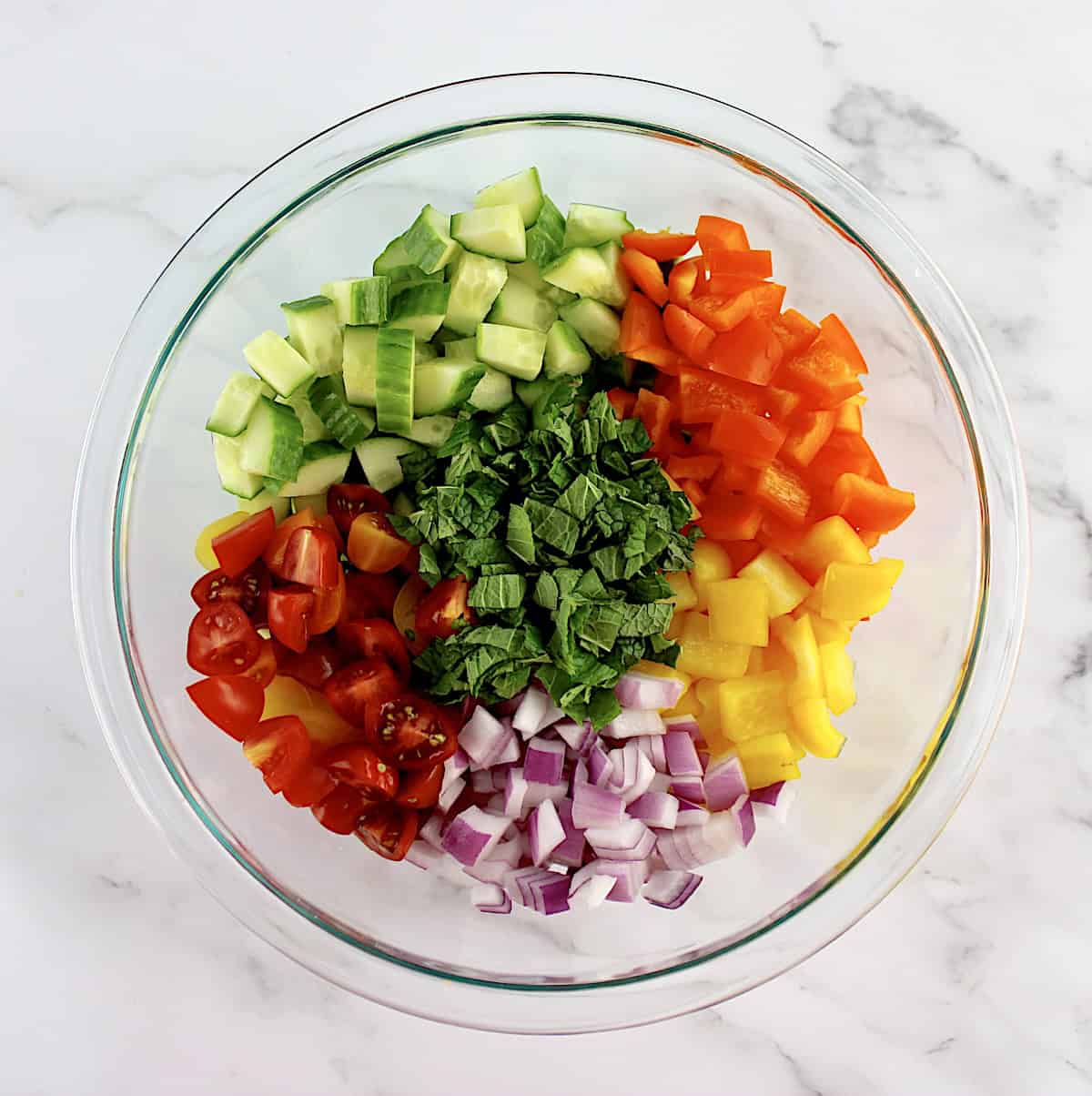 Israeli Salad ingredients in groups in glass bowl unmixed