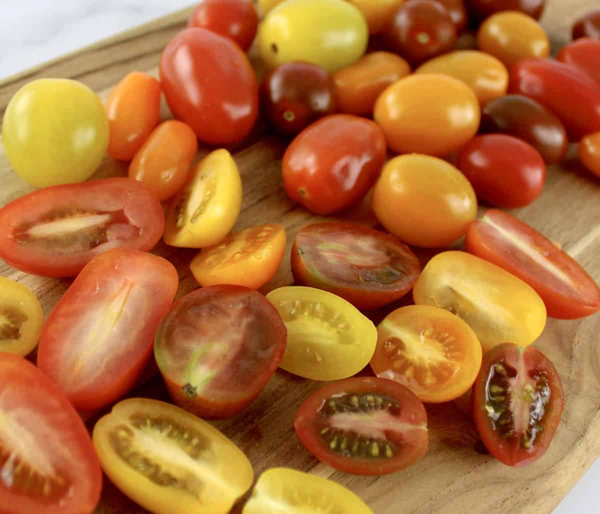 mix of colored tomatoes on cutting board, some sliced in half