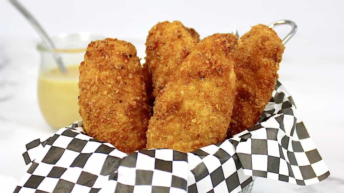 closeup of chicken tenders in white dish with honey mustard on side