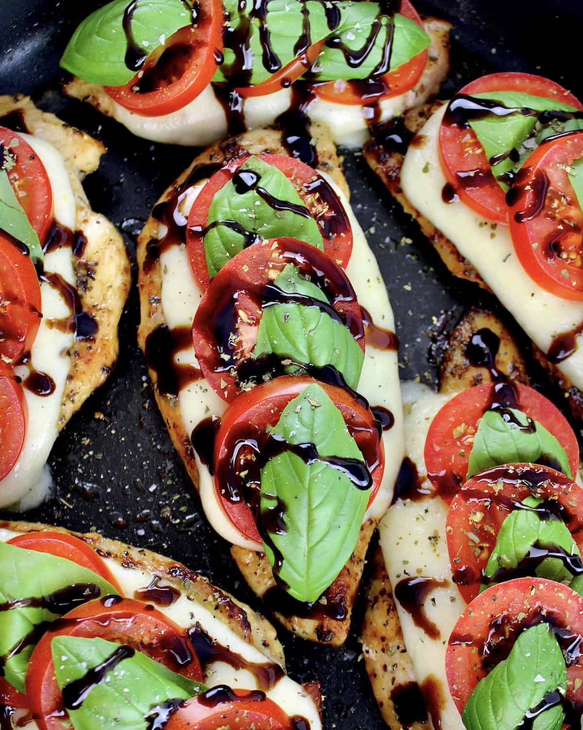 Chicken Caprese in skillet with balsamic glaze drizzled on top