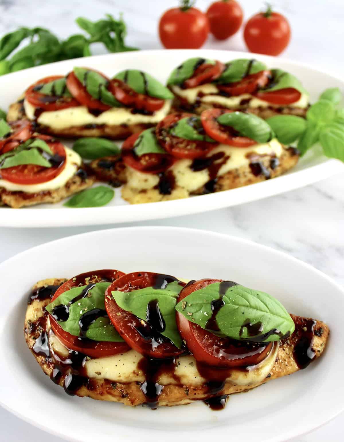 Chicken Caprese on small over plate with balsamic drizzle with platter in back