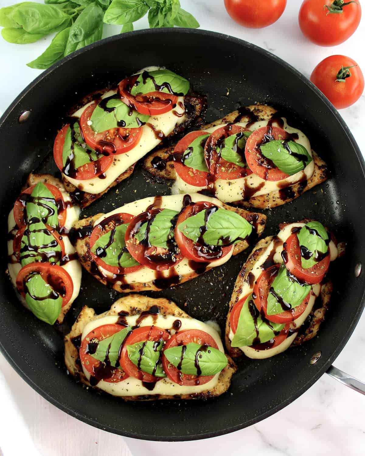 overhead view of 6 pieces of Chicken Caprese in skillet with balsamic drizzle on top