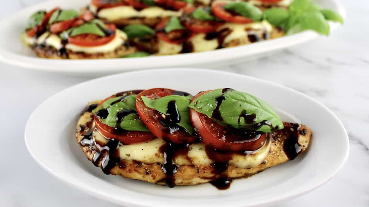 closeup of Chicken Caprese on white plate with balsamic drizzle