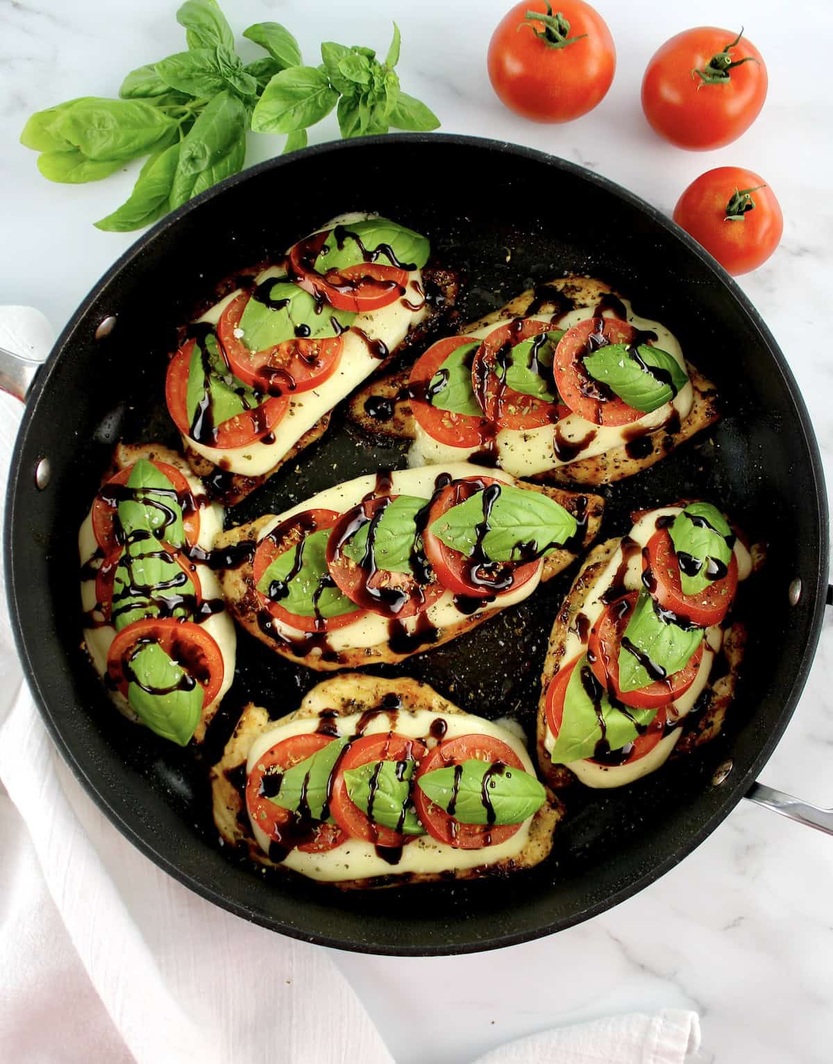 overhead view of 6 pieces of Chicken Caprese in skillet with balsamic drizzle on top