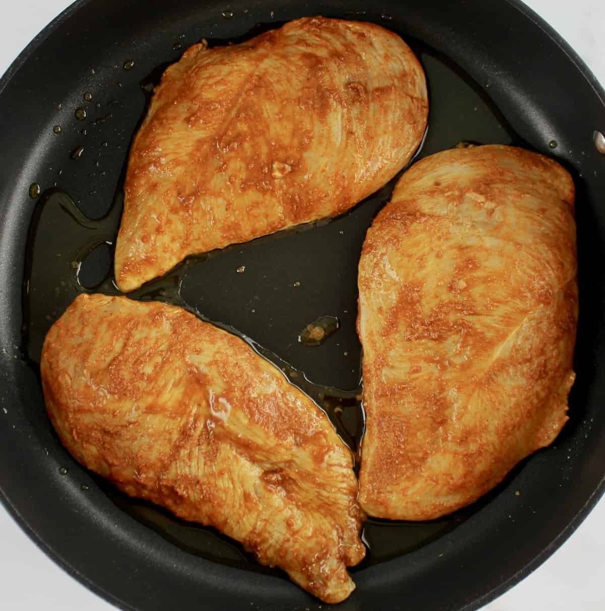 3 raw chicken breasts with fajita spice rub in skillet