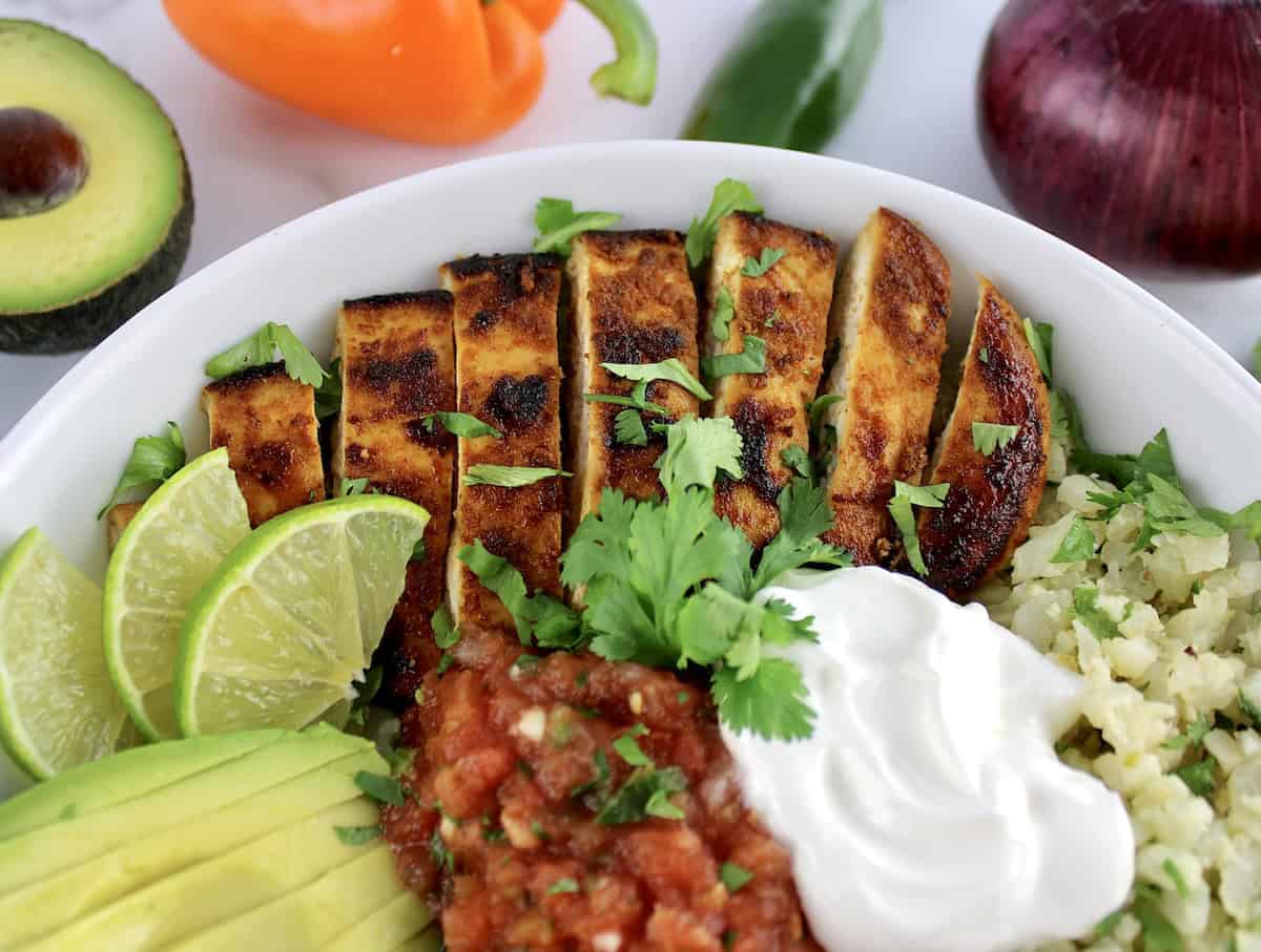 closeup of Chicken Fajita Bowl with sliced chicken lime salsa and avocado