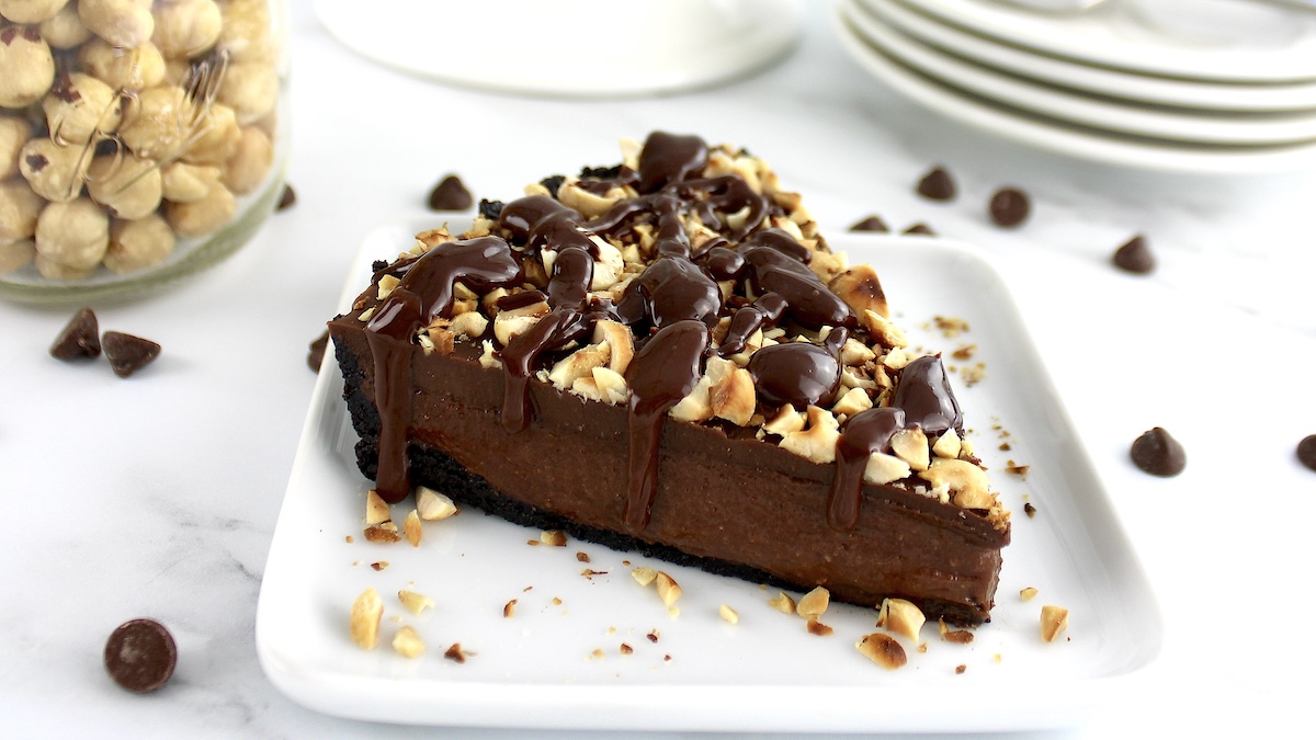 closeup of slice of Chocolate Hazelnut Tart on white plate