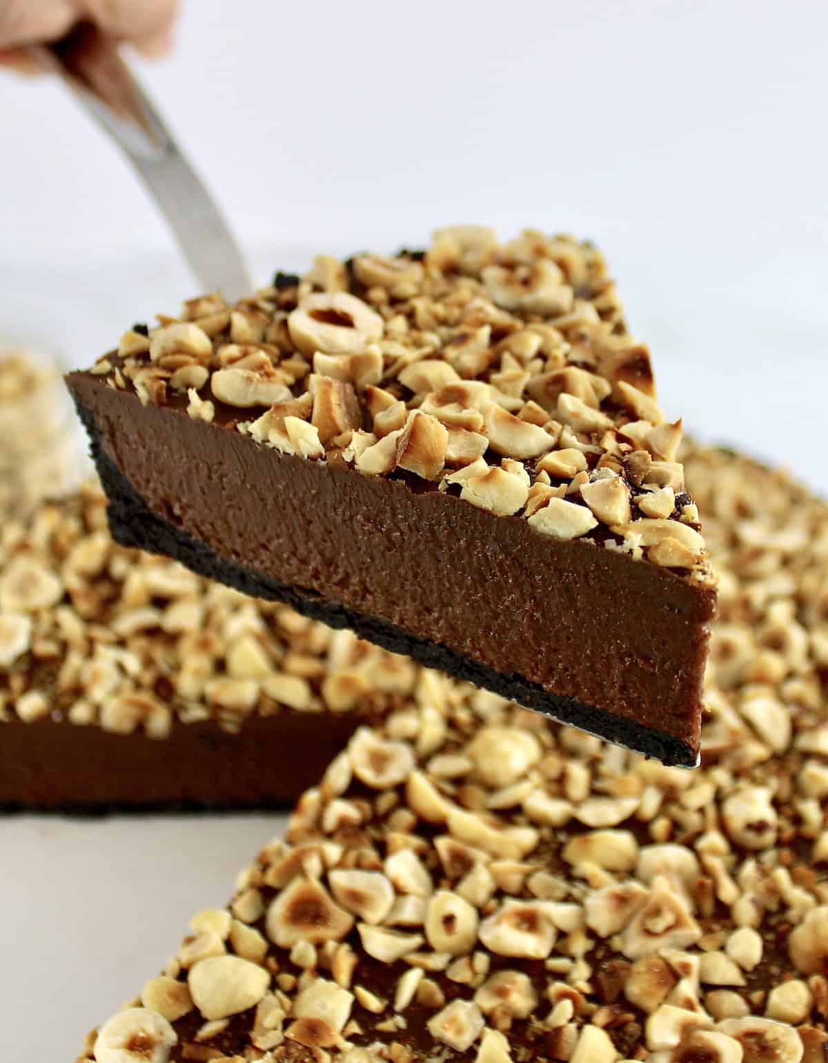 closeup of slice of Chocolate Hazelnut Tart held up with pie server over tart