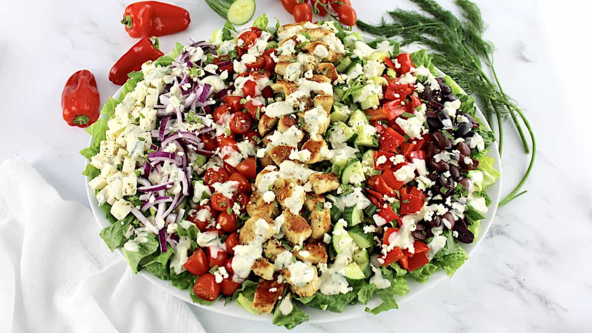 overhead view of Greek Chicken Salad on oval platter with ingredients arranged in rows