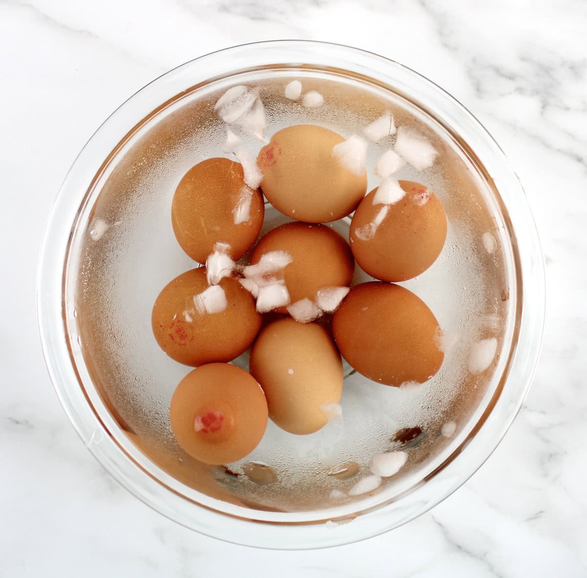 8 whole eggs in ice water in glass bowl