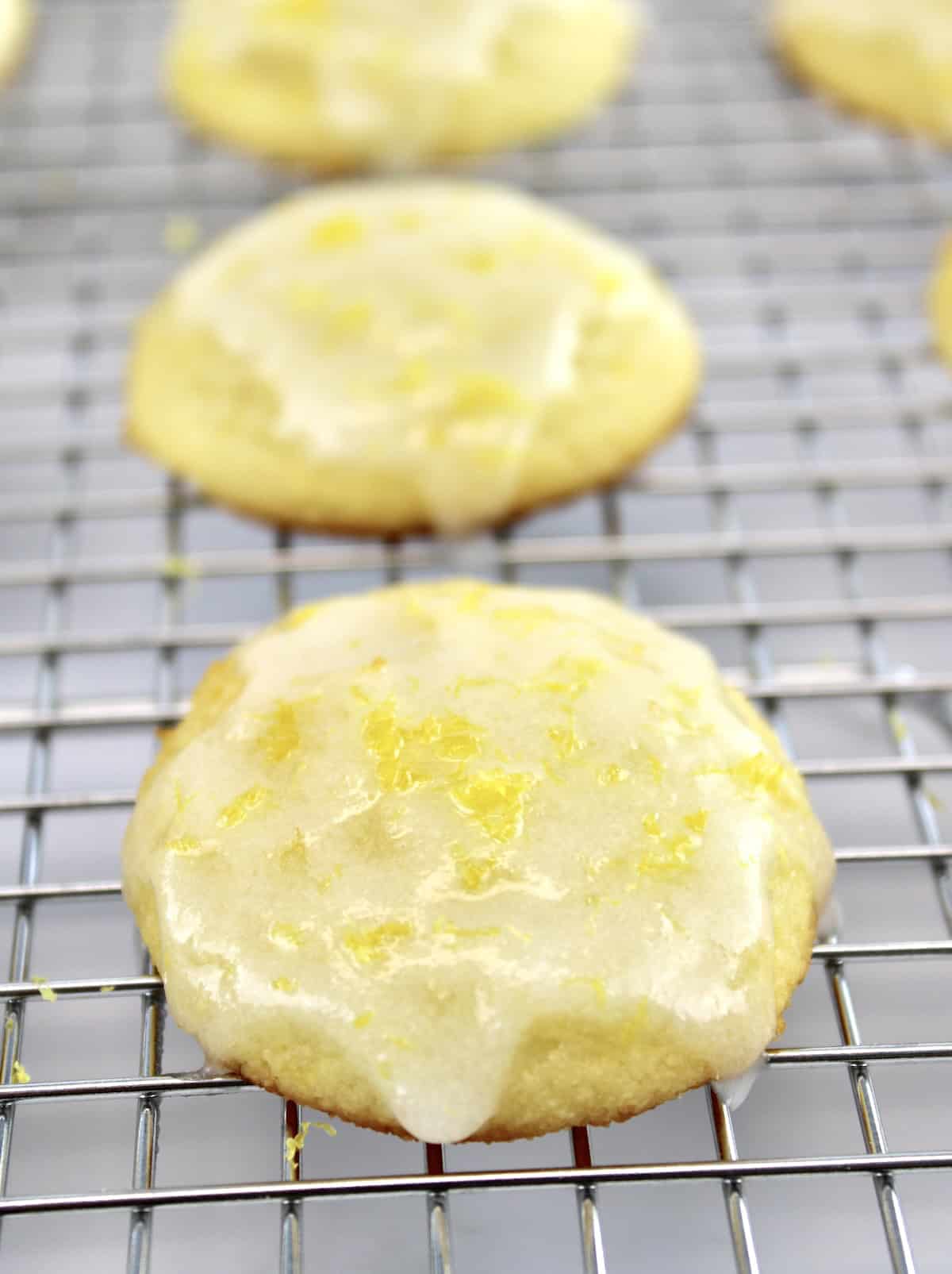 closeup of lemon ricotta cookies with glaze on cooking rack