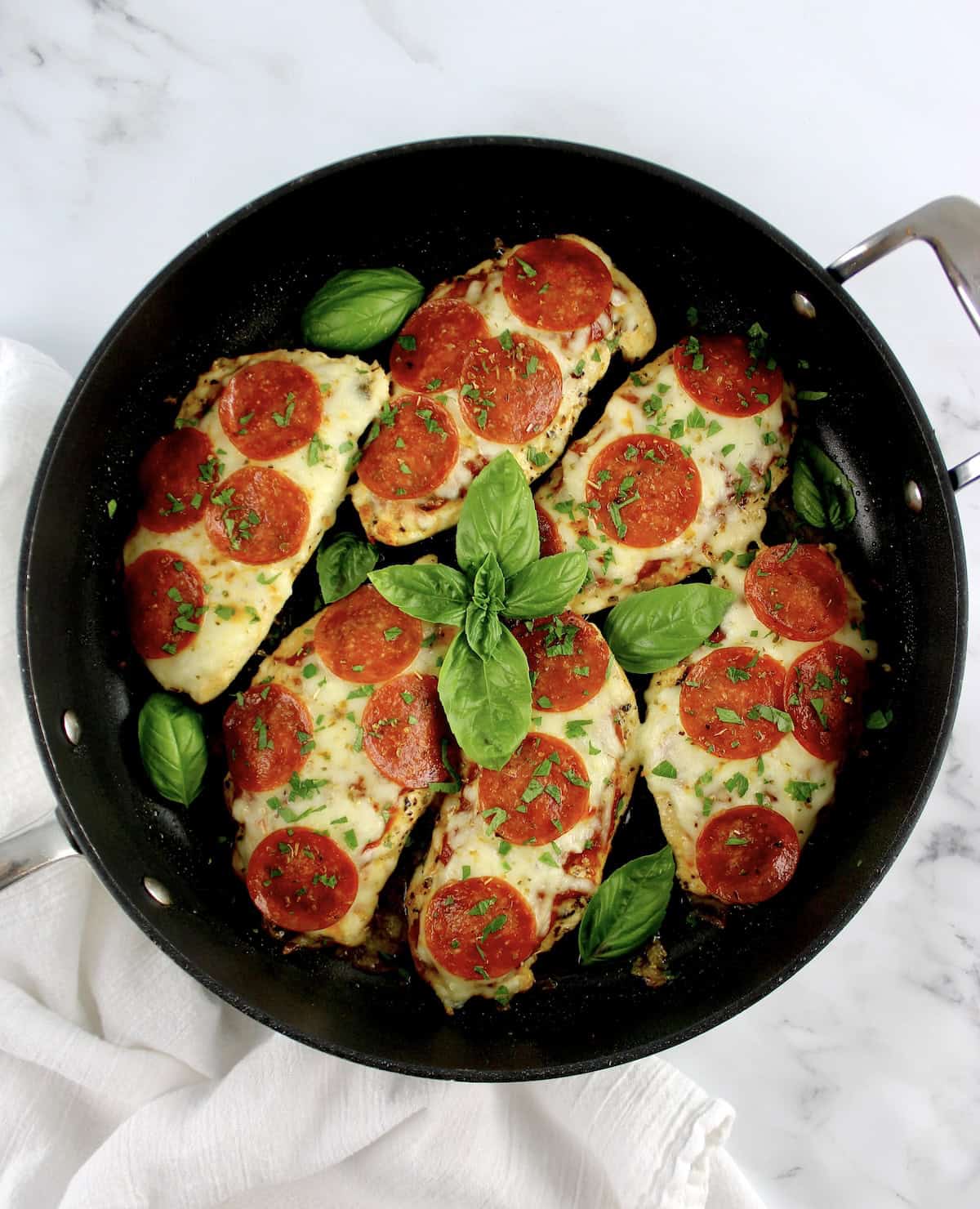 6 pieces of Pizza Chicken in skillet with fresh basil garnish