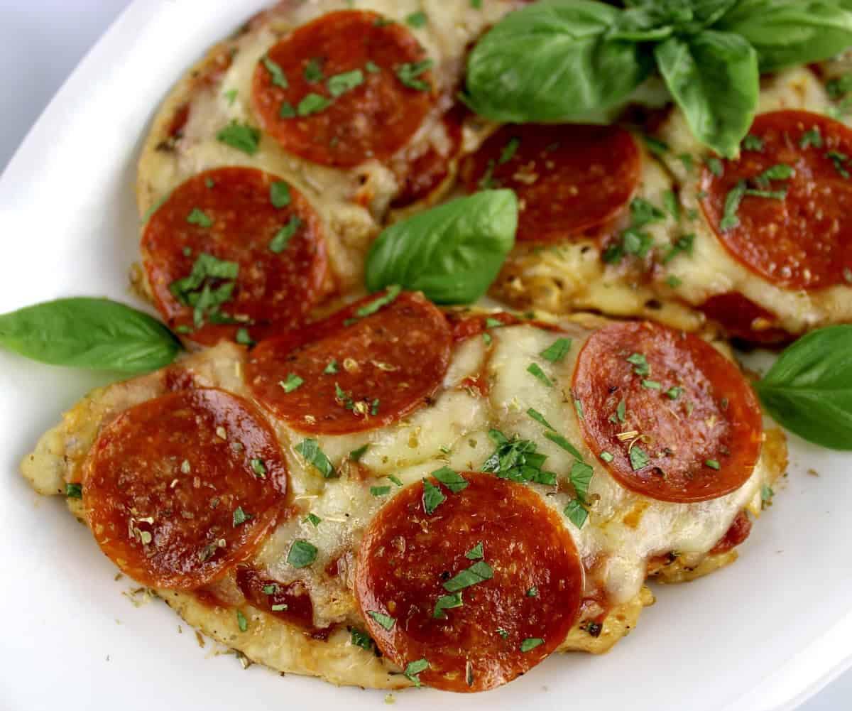 closeup of Pizza Chicken in white oval platter with fresh basil garnish